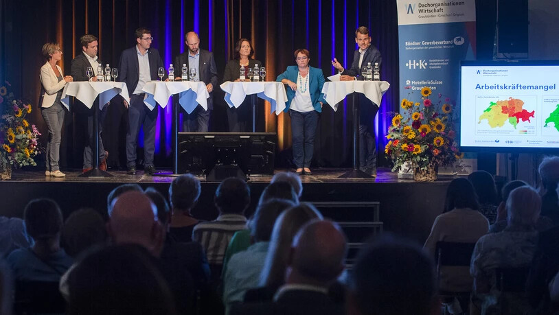 Das überparteiliche Podium mit den sechs Nationalratskandidatinnen und Nationalratskandidaten Anita Mazzetta, Jon Pult, Kevin Brunold, Walter von Ballmoos, Anna Giacometti, Magdalena Martullo-Blocher und Moderator Roger Aebli (von links).