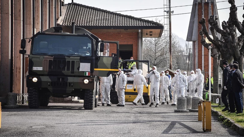 Dramatische Szene: Militär und medizinisches Personal stehen am 28. März 2020 vor der Kirche San Giuseppe in Seriate in der Provinz Bergamo, Italien, während Särge von Menschen, die am Coronavirus verstorben sind, zur Segnung in die Kirche getragen werden. 