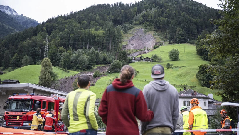 Der Rutsch bewegt: Menschen bestaunen die von Geröll- und Schlammmassen verdeckten Häuser in Schwanden. Der Rutsch bewegt: Menschen bestaunen die von Geröll- und Schlammmassen verdeckten Häuser in Schwanden.