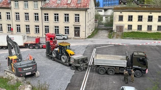 Ein Kommen und Gehen: Auf dem Umschlagplatz steht der erste Bagger (links), der am Montag vom Bauunternehmer angeliefert wurde, dahinter wird eine der beiden Spezialmaschinen der Armee für den Abtransport verladen.