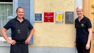 Sie sind stolz auf ihren Erfolg: Stefan Rehli und Ramona Schneider zeigen die Auszeichnungen an der Hauswand ihres «Löwen» in Walenstadt. 